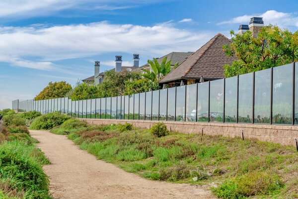 Narrow pathway in front of homes under cloudy blue sky in a seaside neighborhood