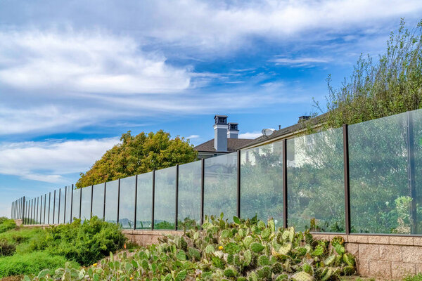 Glass fence in front of houses against cloudy blue sky in Huntington Beach CA