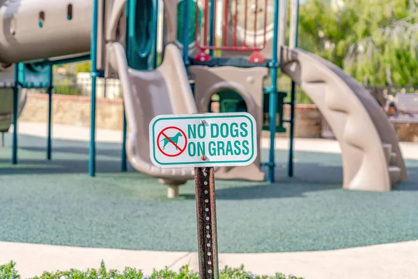 No Dogs On Grass firma contra parque infantil borroso en Huntington Beach California — Foto de Stock