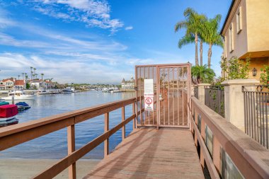 Boat dock at shore of sea reflecting blue sky in Huntington Beach California