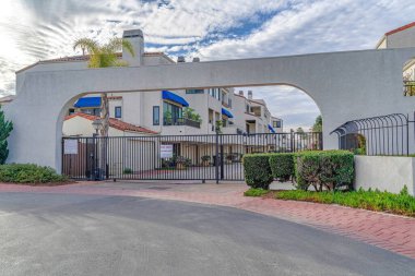 Gated entrance at a neighborhood in Huntington Beach under cloudy blue sky