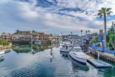 People on paddle boards against houses with private docks in Huntington Beach