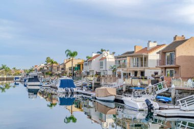 Homes with private docks on clear sea with boats and reflecting cloudy skyscape