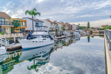 Overcast sky over houses overlooking scenic canal with boats and private docks