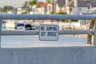 No Jumping sign on the metal railing of bridge over water in Huntington Beach CA