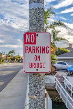 No Parking On Bridge sign against road and cloudy blue sky in Huntington Beach