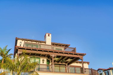 Koyun pencere balkonları ve açık mavi gökyüzüne karşı bacası olan güzel bir ev.