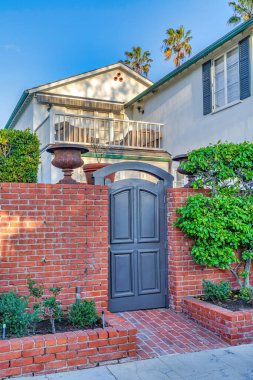 San Diego California 'daki ev gri kemerli ahşap kapılı ve kırmızı tuğlalı çitli.