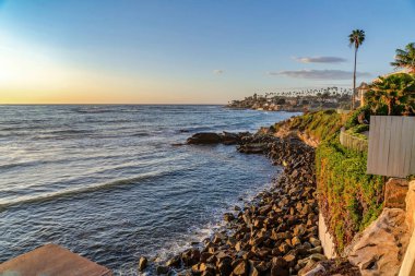 Dalgalanan okyanus ve mavi gökyüzü San Diego California 'da gün batımında altın parıldıyor.