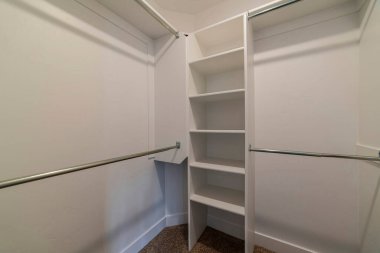 Evin içinde çok katmanlı açık raflar ve giysi çubuğu olan boş dolap.