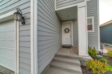 Beyaz ahşap ön kapısı ve garaj kapısı olan bir evin girişi.