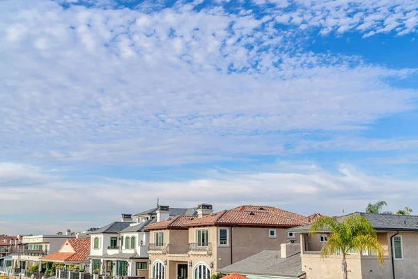 Blå himmel og oppustede skyer over huse i et prestigefyldt badekvarter - Stock-foto