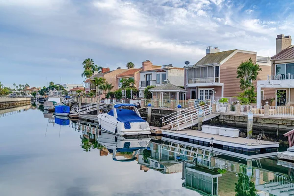 Huizen met prive-dokken grenzend aan het kanaal met reflectie van bewolkte lucht — Stockfoto