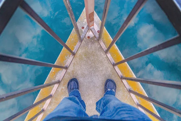 Человек, стоящий на углу палубы у гавани с отражением неба — стоковое фото