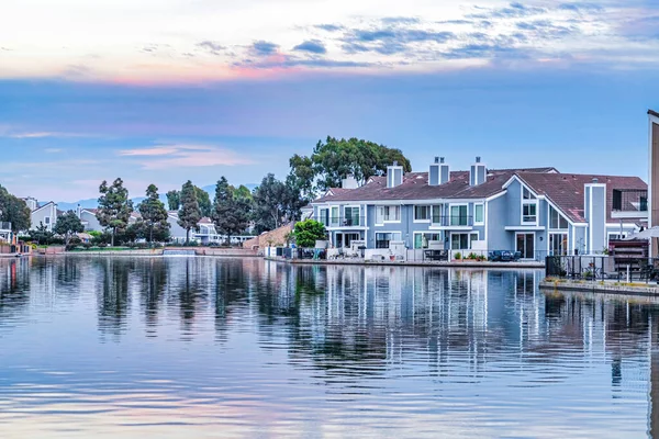 Bayfront huizen met uitzicht op de kalme zee die de bewolkte lucht weerspiegelt bij zonsondergang — Stockfoto