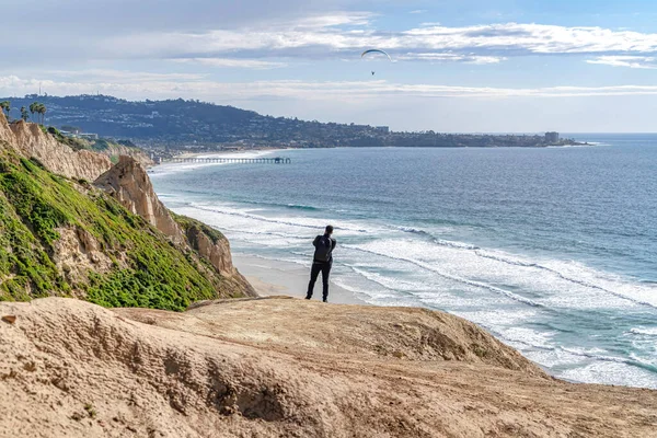 Homem na montanha com vista para o oceano com cais e parachuters em San Diego — Fotografia de Stock