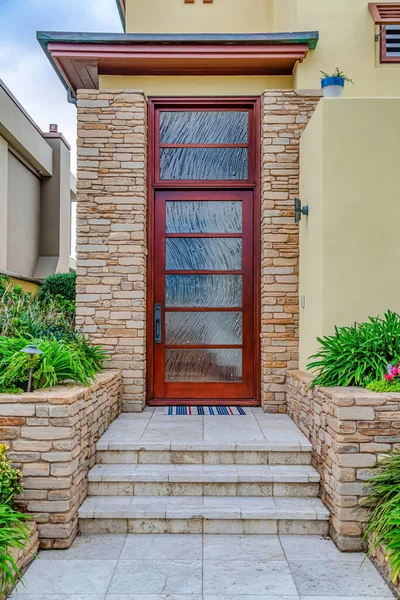 Front door with frosted glass insets and transom window at the facade of house