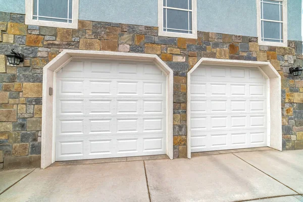 Garage extérieur attaché à deux voitures avec portes blanches contre le mur de pierre d'une maison — Photo