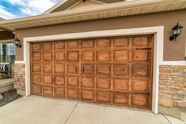 Amplia puerta de garaje con paneles de madera marrón de un garaje adjunto con lámparas de pared — Foto de Stock