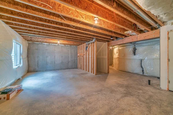 Room under construction with plastic cover on wall and exposed wood beams — Stock Photo, Image