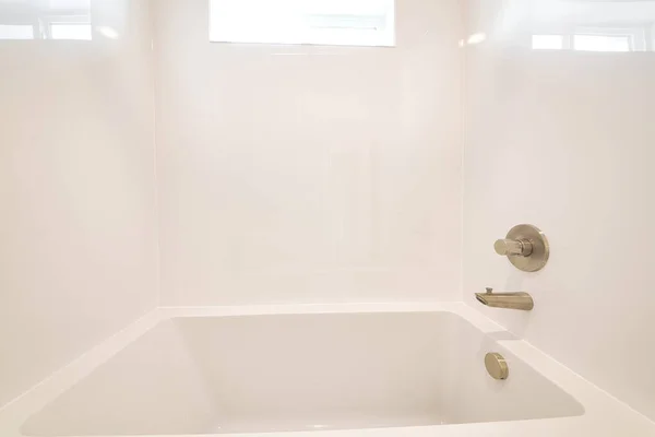 Čistá koupelna s perlivou vestavěnou vanou a lesklé bílé dlaždice ve zdi — Stock fotografie