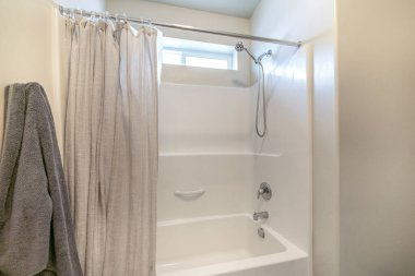 Banyo içi küvet duş ve pencere kombinasyonuyla dolu.