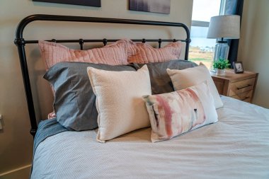 Bir evin yatak odasında siyah metal çerçeveli rahat bir yatak ve yumuşak yastıklar.