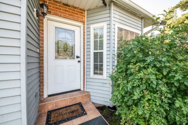 Ön kapının dış tarafında tuğlalar ve vinil kaplama duvarlar var.