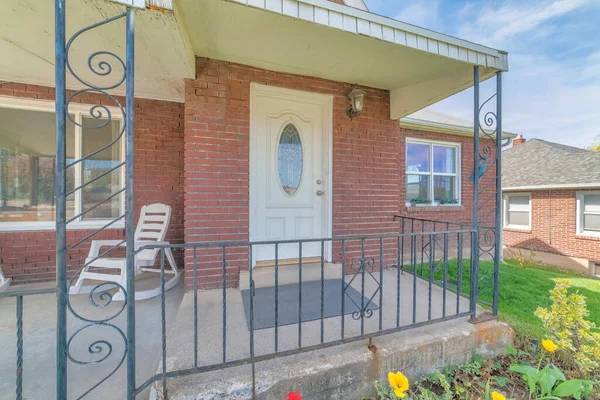 White door with oval glass pane against red brick wall at the front of a house — Stock Photo, Image