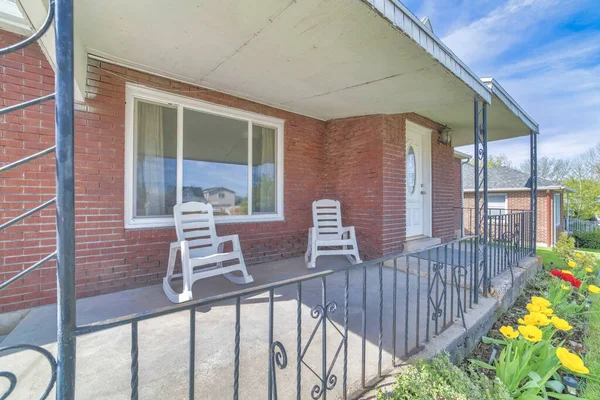 Rocking chairs on the front porch of a house with red brick wall and white door — Stock Photo, Image