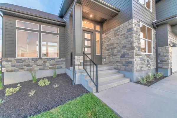 Two storey home facade with stone brick wall and glass paned gray front door — Stock Photo, Image