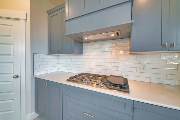 Cuisinière fixée sur le comptoir de cuisine avec hotte aspirante et armoires grises — Photo