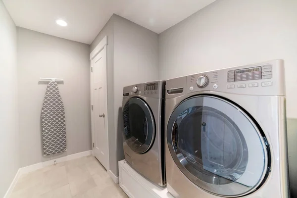 Light gray laundry room with tiles, washer, dryer and storage room — Stock Photo, Image