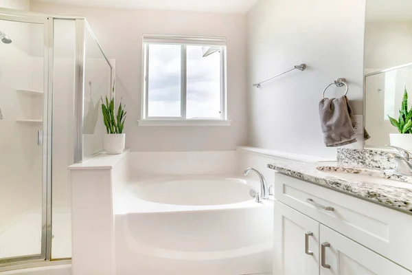 White bathroom with tub, shower stall with glass and vanity cabinet with marble top, sink and mirror — Stock Photo, Image