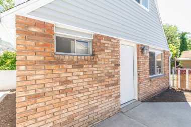 Duvarları, tuğlaları ve pencereleri olan küçük bir misafir evinin yan tarafında.