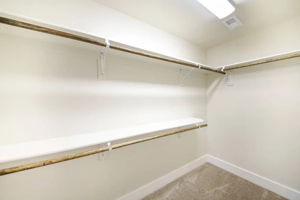 Empty walk-in closet with white walls and carpeted floor