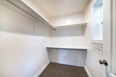 Koyu kahverengi halı döşemeleri, duvara asılmış raflar ve kancalarla dolaba gir.