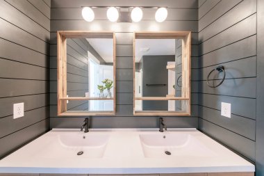 Çevredeki yıldırımlarla çift lavabo ve yatay çizgili gri duvarlar.