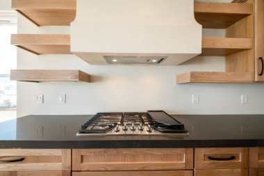 Siyah döşeme tezgahı ve ahşap dolabı olan fırın.