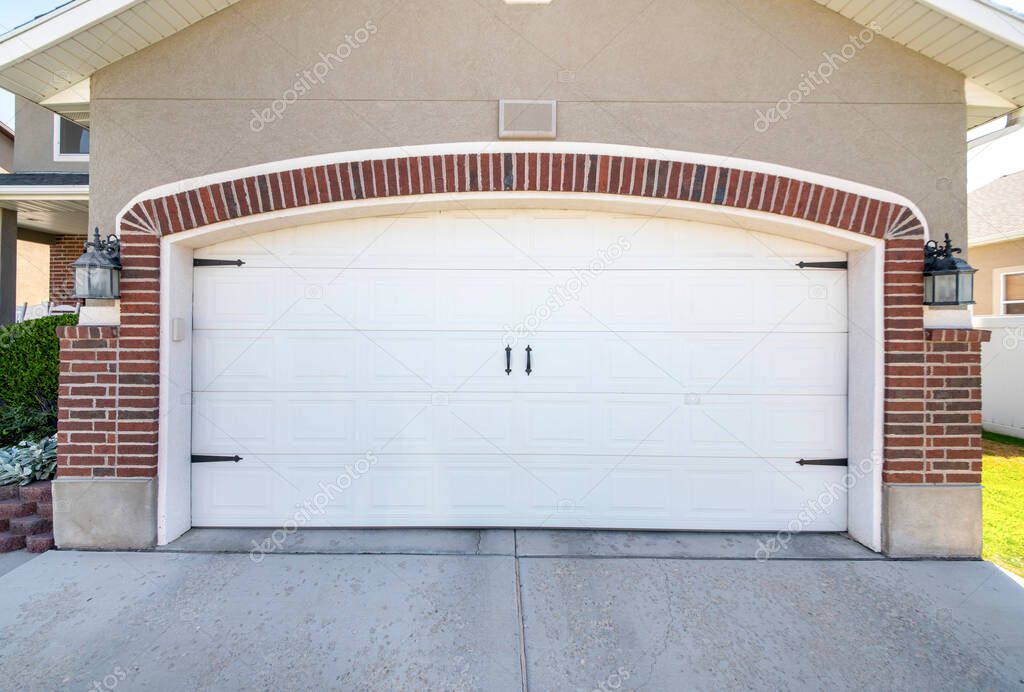 Closed carriage style white garage door of a house with bricks
