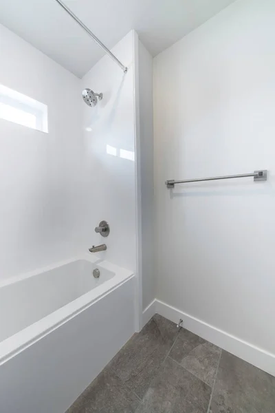 Vasca da bagno all'interno di un bagno con pavimenti in piastrelle grigio scuro e parete bianca — Foto Stock