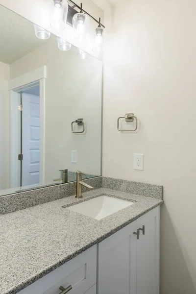 Vanity sink of a bathroom with granite countertop and wall mounted lights