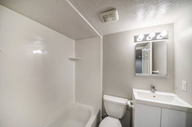 Gösterişli lavabosu ve aynası olan küçük, beyaz bir banyo.