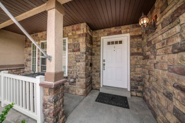 Beyaz kapısı ve taş duvarları olan bir evin önünde.