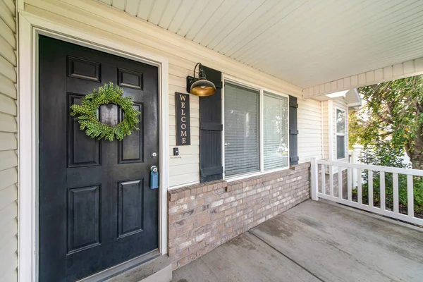 Haustür außen mit Laubkranz, hölzernem weißen Geländer und Mauerziegeln — Stockfoto