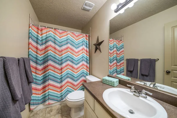 Intérieur de la salle de bain avec lavabo et rideau de douche à motifs zigzag coloré — Photo