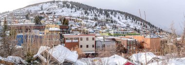 Utah 'taki Park City' de karla kaplı bir tepede renkli evler ve binalar.