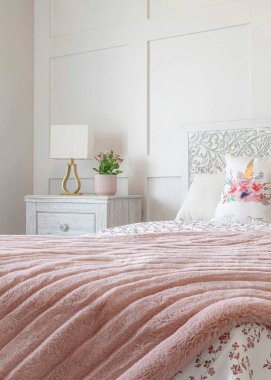 Dikey kadınsı yatak odası çiçek çarşafı ve duvara dayalı pembe battaniye.