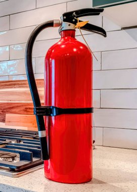 Ev mutfağının içindeki tezgahta su ısıtıcısı ve tenceresi olan dikey yangın söndürücü.