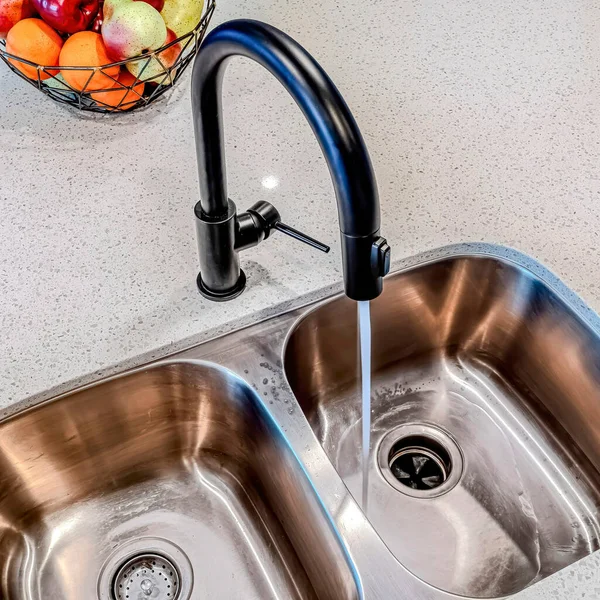 Square Water from black curved faucet running down stainless steel sink with two bowls — Stock Photo, Image